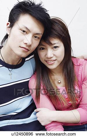 Stock Photograph - Portrait of a young couple sitting together smiling. Fotosearch
