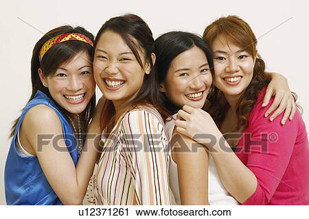 Stock Image - Portrait of four young women hugging each other and posing. Fotosearch
