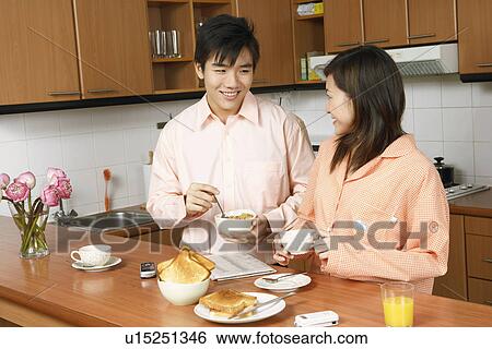 Young couple looking at each other and smiling at a kitchen counter View Large Photo Image Stock Photograph - Young couple looking at each other and smiling at a kitchen counter. Fotosearch