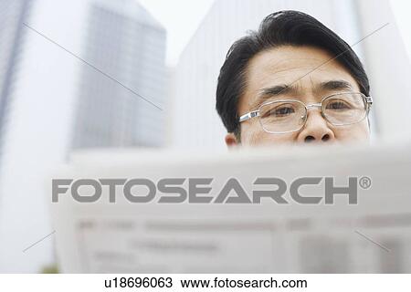 Stock Image - Close-up of a mature man reading a newspaper. Fotosearch