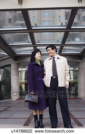 Stock Image - Low angle view of a mature couple looking at each other smiling. Fotosearch