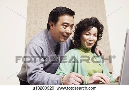 Low angle view of a mature couple using a laptop View Large Photo Image Stock Photo - Low angle view of a mature couple using a laptop. Fotosearch