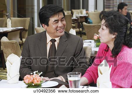 Mature couple sitting in a restaurant looking at each other View Large Photo Image Stock Photograph - Mature couple sitting in a restaurant looking at each other. Fotosearch