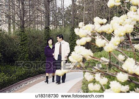 Stock Image - Mature couple walking in a garden. Fotosearch