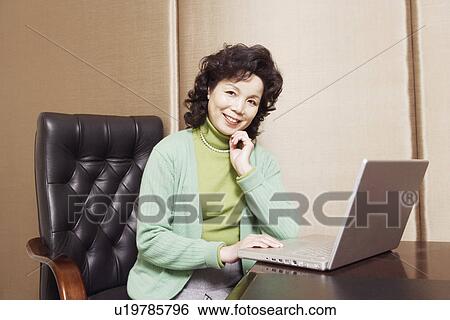 Portrait of a businesswoman sitting in front of a laptop View Large Photo Image Stock Photograph - Portrait of a businesswoman sitting in front of a laptop. Fotosearch