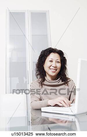 Stock Photography - Portrait of a businesswoman using a laptop smiling. Fotosearch