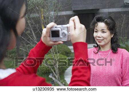 Stock Photography - Rear view of a daughter taking a photograph of her mother. Fotosearch