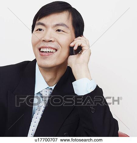 Stock Photo - Close-up of a businessman sitting on a couch and talking on a mobile phone. Fotosearch