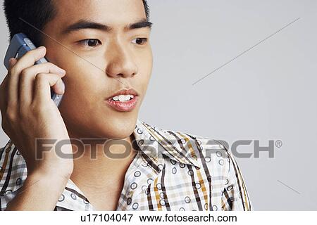 Close-up of a young man talking on a mobile phone View Large Photo Image Stock Photo - Close-up of a young man talking on a mobile phone. Fotosearch