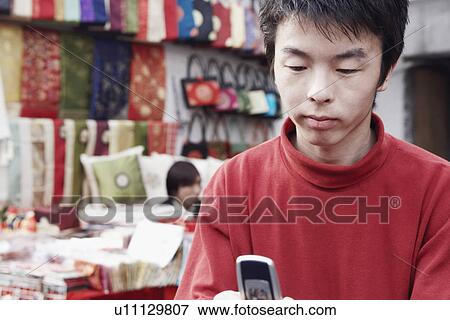 Stock Photo - Close-up of a young man using a mobile phone. Fotosearch