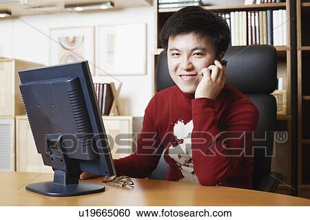 Portrait of a businessman sitting in front of a computer monitor using a mobile phone View Large Photo Image Stock Image - Portrait of a businessman sitting in front of a computer monitor using a mobile phone. Fotosearch