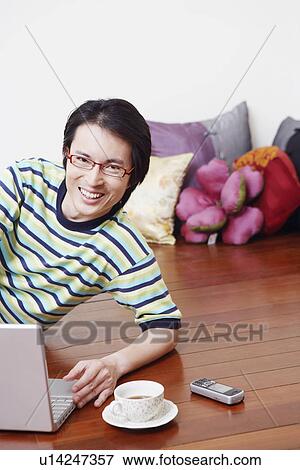 Stock Photo - Portrait of a mid adult man leaning in front of a laptop and smiling. Fotosearch