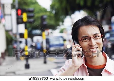 Stock Image - Portrait of a mid adult man talking on a mobile phone and smiling. Fotosearch