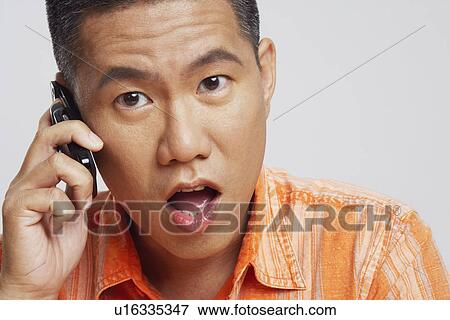 Portrait of a mid adult man talking on a mobile phone and looking surprised View Large Photo Image Stock Photo - Portrait of a mid adult man talking on a mobile phone and looking surprised. Fotosearch