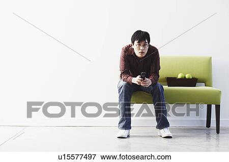 Stock Photo - Portrait of a young man holding a mobile phone. Fotosearch