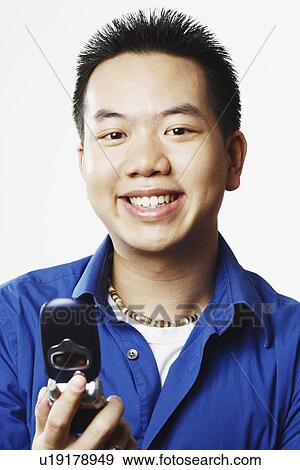 Portrait of a young man holding a mobile phone View Large Photo Image Stock Photo - Portrait of a young man holding a mobile phone. Fotosearch