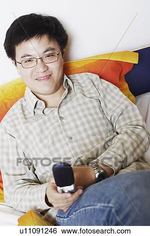 Portrait of a young man holding a mobile phone smiling View Large Photo Image Stock Photograph - Portrait of a young man holding a mobile phone smiling. Fotosearch