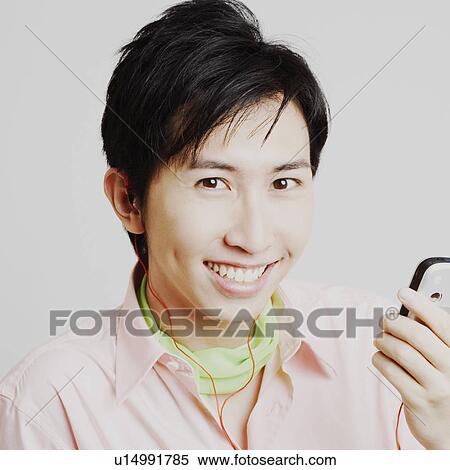 Stock Photography - Portrait of a young man listening to music on a mobile phone. Fotosearch
