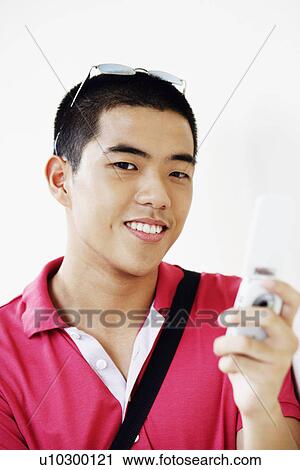 Stock Image - Portrait of a young man operating a mobile phone. Fotosearch