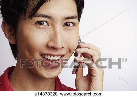 Portrait of a young man smiling and talking on a mobile phone View Large Photo Image Stock Photo - Portrait of a young man smiling and talking on a mobile phone. Fotosearch