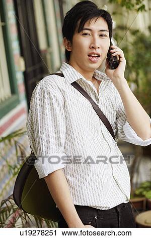 Stock Image - Portrait of a young man talking on a cordless phone. Fotosearch