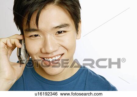 Stock Photograph - Portrait of a young man talking on a mobile phone and smiling. Fotosearch