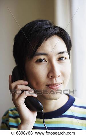 Stock Image - Portrait of a young man talking on the telephone. Fotosearch