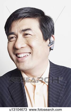 Stock Image - Close-up of a businessman wearing a hands free device smiling. Fotosearch