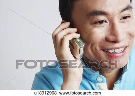 Close-up of a young man talking on a mobile phone and smiling View Large Photo Image Stock Photo - Close-up of a young man talking on a mobile phone and smiling. Fotosearch