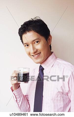 Stock Image - Portrait of a businessman drinking a cup of black tea and smiling. Fotosearch