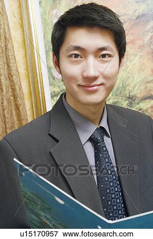Stock Photo - Portrait of a businessman holding a file smiling. Fotosearch