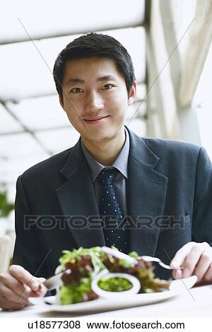Stock Photo - Portrait of a businessman seated at the table in a restaurant smiling. Fotosearch