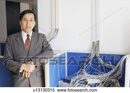 Stock Photography - Portrait of a businessman standing in a server room smiling. Fotosearch