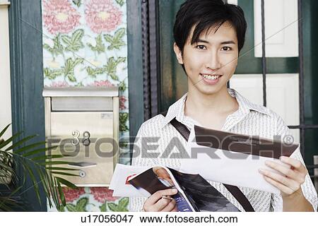 Portrait of a young man holding mail and smiling View Large Photo Image Stock Photo - Portrait of a young man holding mail and smiling. Fotosearch