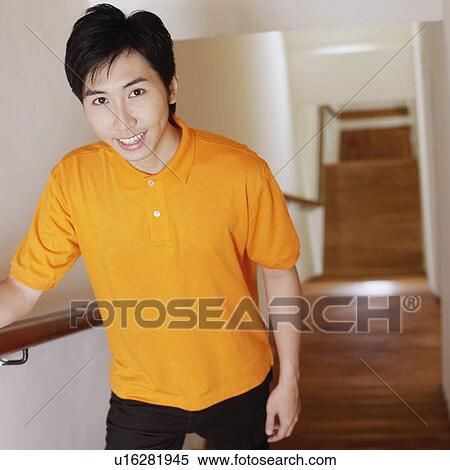 Stock Photography - Portrait of a young man walking up stairs and smiling. Fotosearch