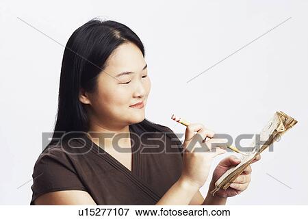 Stock Photo - Close-up of a mid adult woman holding a book with a pencil and smiling. Fotosearch