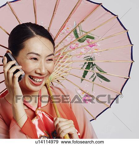 Stock Photo - Close-up of a mid adult woman talking on a mobile phone and smiling. Fotosearch