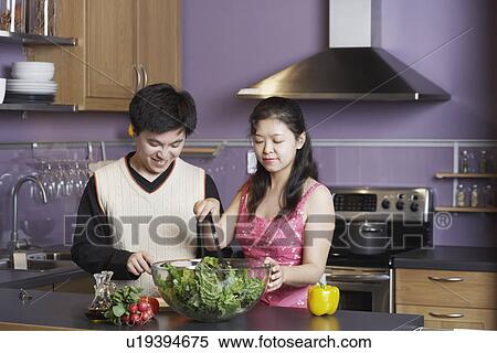 Stock Photography - Close-up of a young man standing with a mid adult woman in the kitchen. Fotosearch