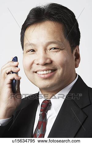 Stock Photography - Portrait of a businessman holding a mobile phone smiling. Fotosearch
