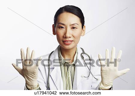 Stock Image - Portrait of a female doctor wearing surgical gloves. Fotosearch
