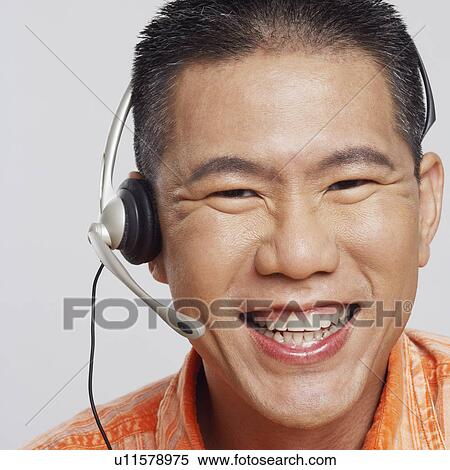 Stock Photography - Portrait of a mid adult man wearing a headset and smiling. Fotosearch