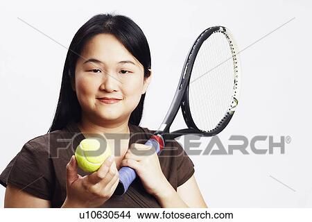 Picture - Portrait of a mid adult woman holding a tennis ball and a tennis racket. Fotosearch