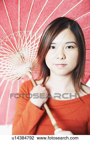 Stock Image - Portrait of a mid adult woman holding a parasol. Fotosearch