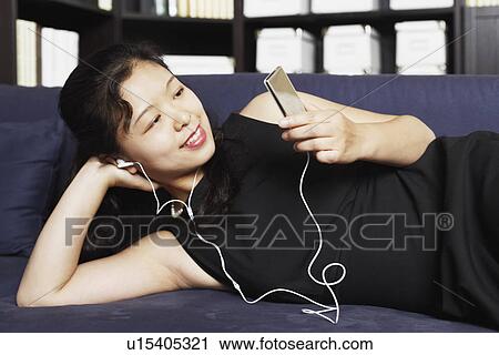 Close-up of a young woman listening to music on headphones View Large Photo Image Stock Image - Close-up of a young woman listening to music on headphones. Fotosearch