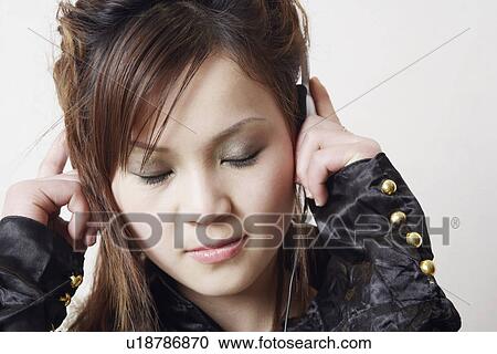 Stock Image - Close-up of a young woman listening to music. Fotosearch