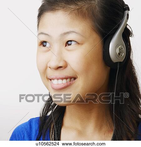 Picture - Close-up of a young woman wearing headphones and listening to music. Fotosearch
