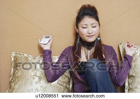 Close-up of a young woman wearing headphones listening to music View Large Photo Image Stock Image - Close-up of a young woman wearing headphones listening to music. Fotosearch