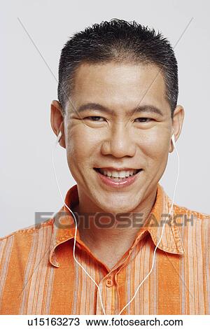 Stock Image - Portrait of a mid adult man wearing headphones and listening to music. Fotosearch