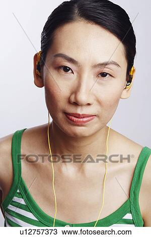 Stock Image - Portrait of a mid adult woman wearing headphones and listening to music. Fotosearch