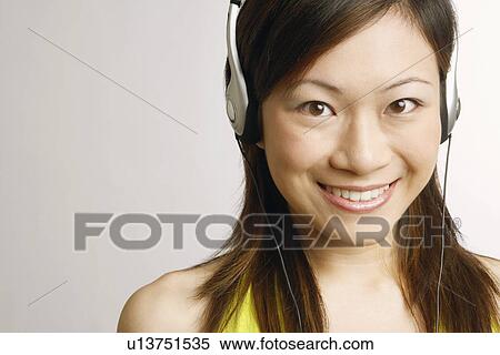 Stock Photography - Portrait of a young woman listening to music and smiling. Fotosearch